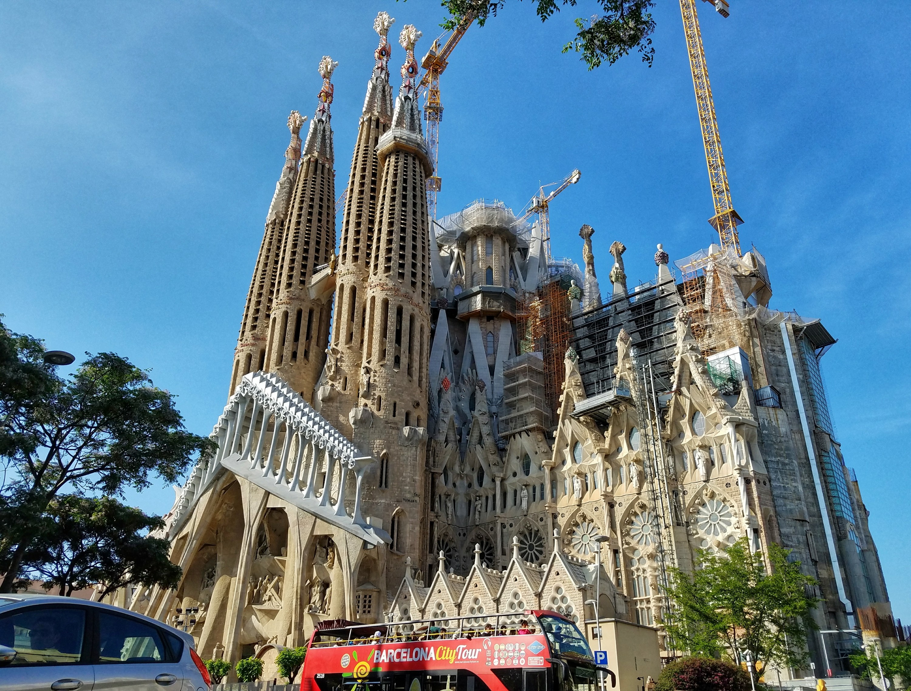 Sagrada Familia in Barcelona Spain with red Barcelona City Tour bus parked in front